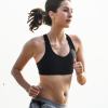 A woman running in the sun wearing a black bra.