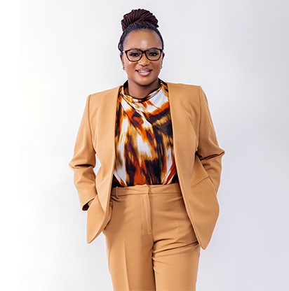 A woman in brown suit and tie standing with hands on hips.