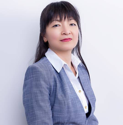 A woman in a blue suit standing next to a white wall.